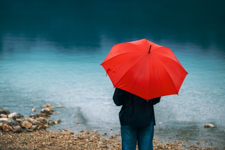 Woman with red umbrella contemplates on rain